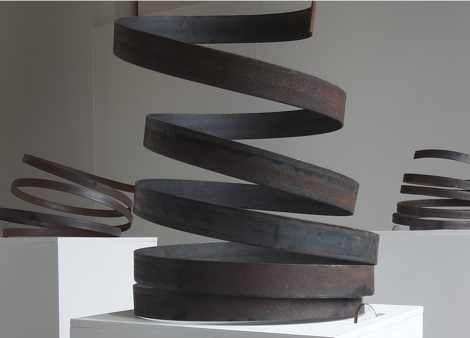 Student work by Caroline Clarke. Large metal spirals on plinths which hide mechatronic devices that nudge and wiggle the spirals, giving them the impression of independent movement