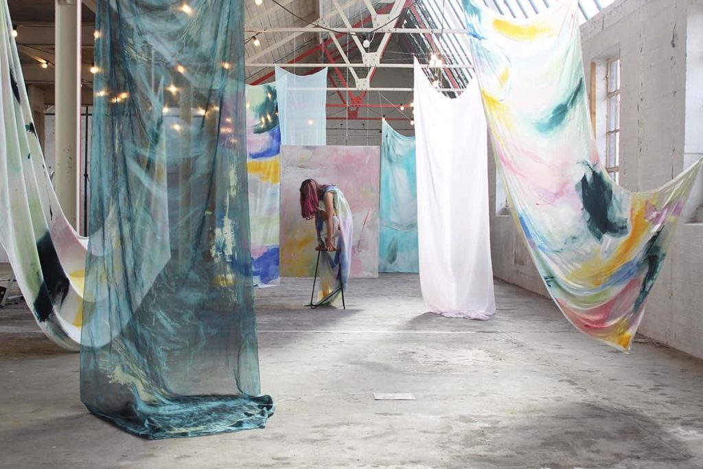 BA Fine Art work by Brooke Savino showing an installation view of a dancer amongst painted fabrics.