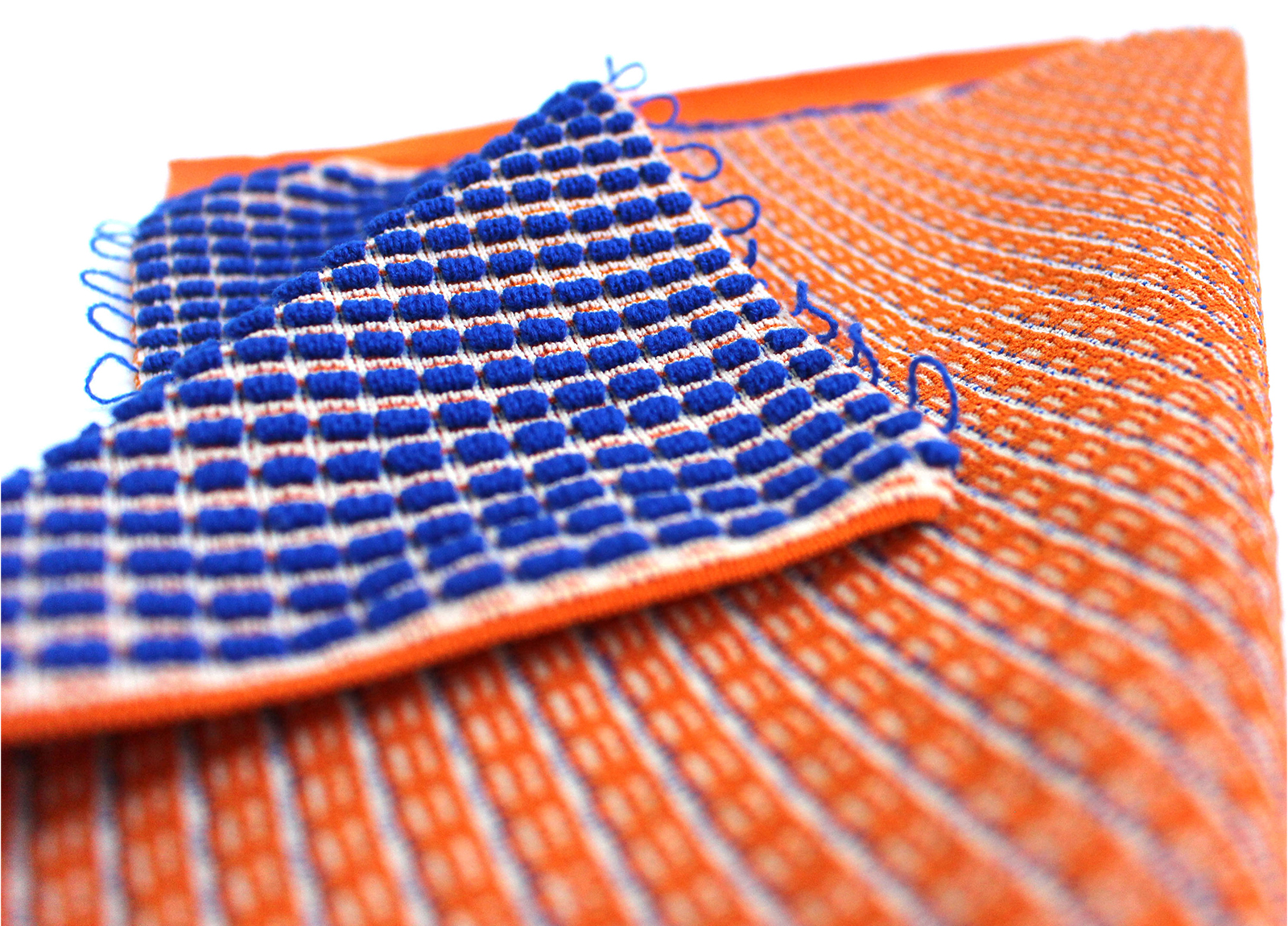 Student work by Kiera Morel. A textured woven fabric which is blue on one side and orange on the other