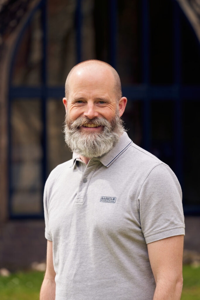 portrait photo of course leader James Smith, with a grey beard and marl grey polo shirt