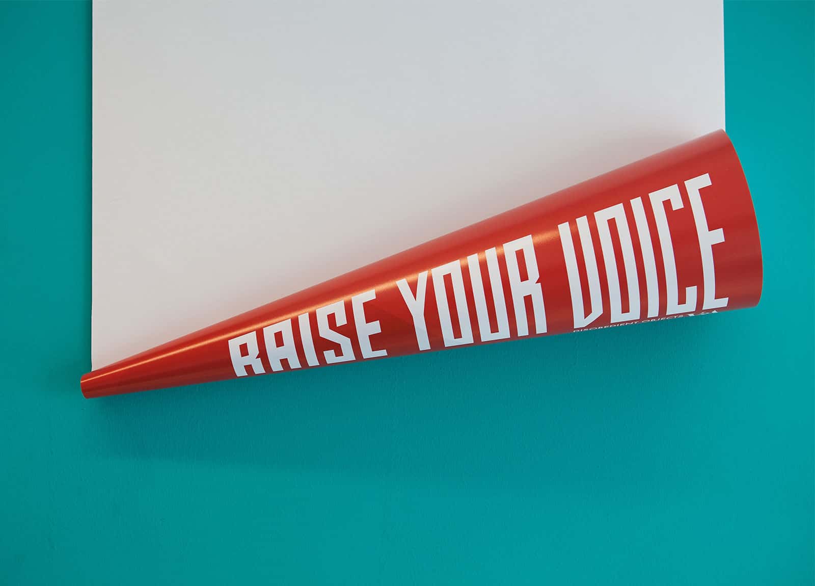 Image of a rolled up poster with the slogan raise your voice printed on it