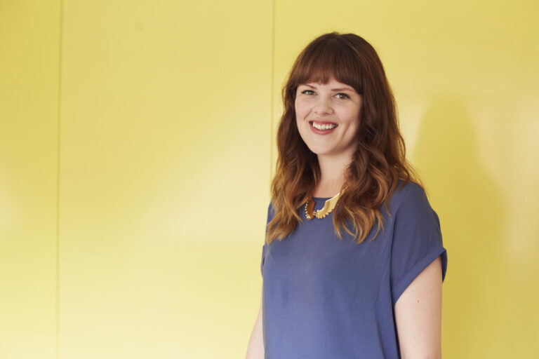 portrait photo of lecturer Helen Piercy with long hair and a blue top smiling at camera