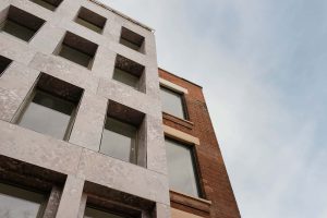 photo of Norwich University of the Arts building Cavendish House shows tall four storey building with red brickwork addition against sky backdrop