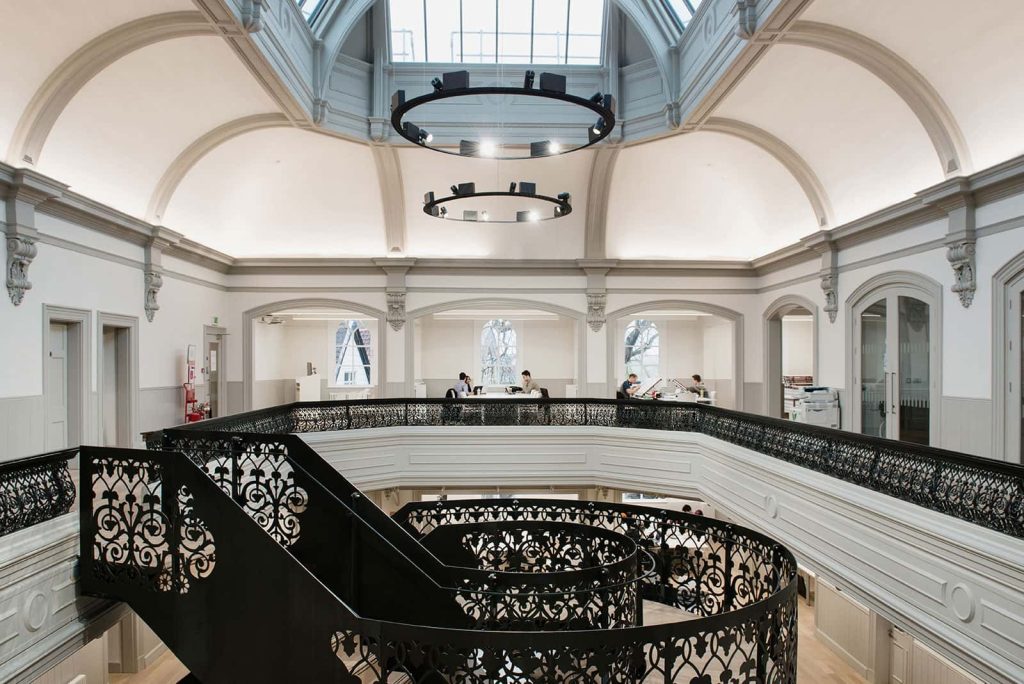 photo of Norwich University of the Arts building boardman house shows large atrium with circular staircase in center with upper level wall with black metal railing and large white curved walls