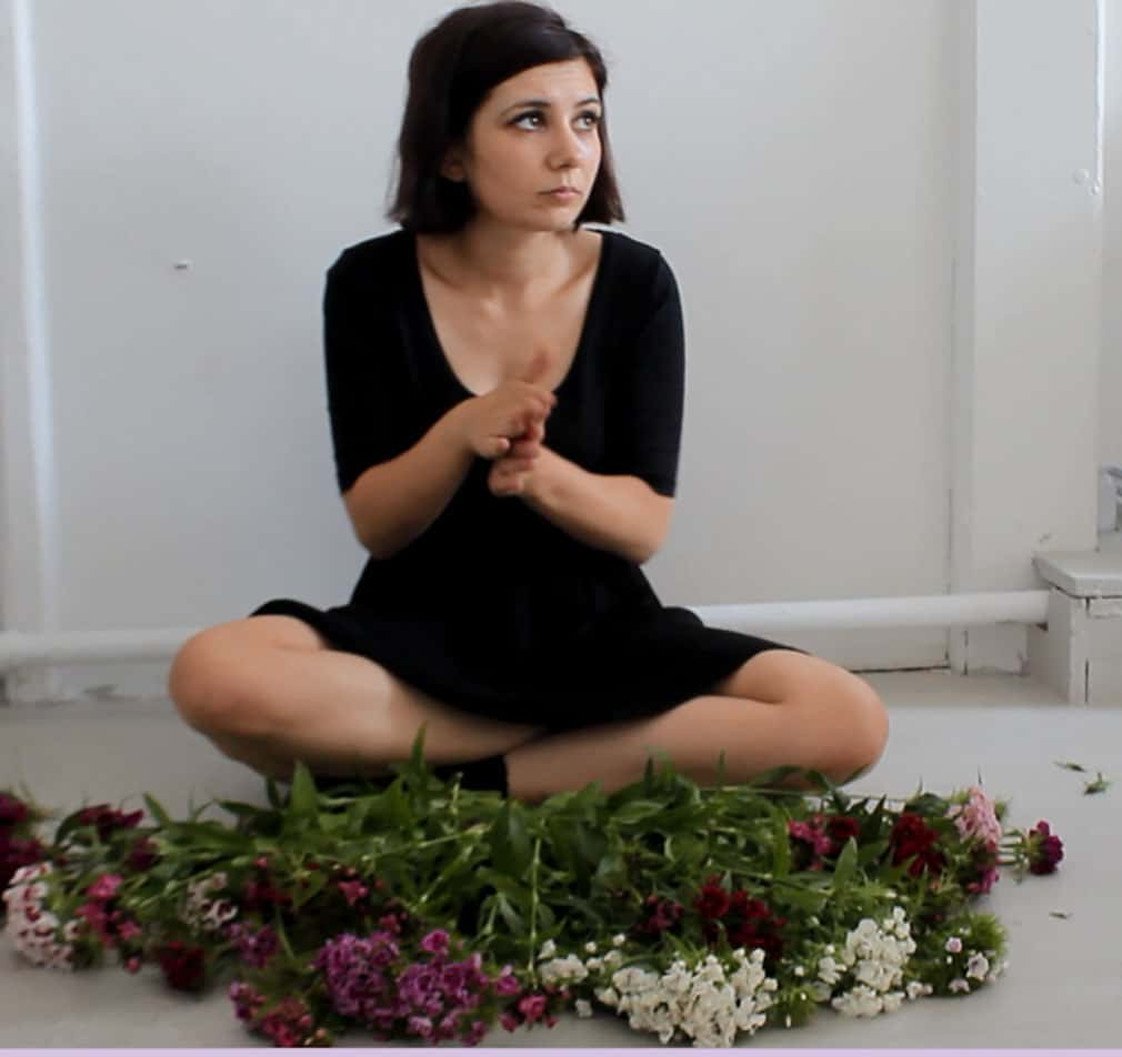 Sitting cross legged in front of an arrangement of flowers