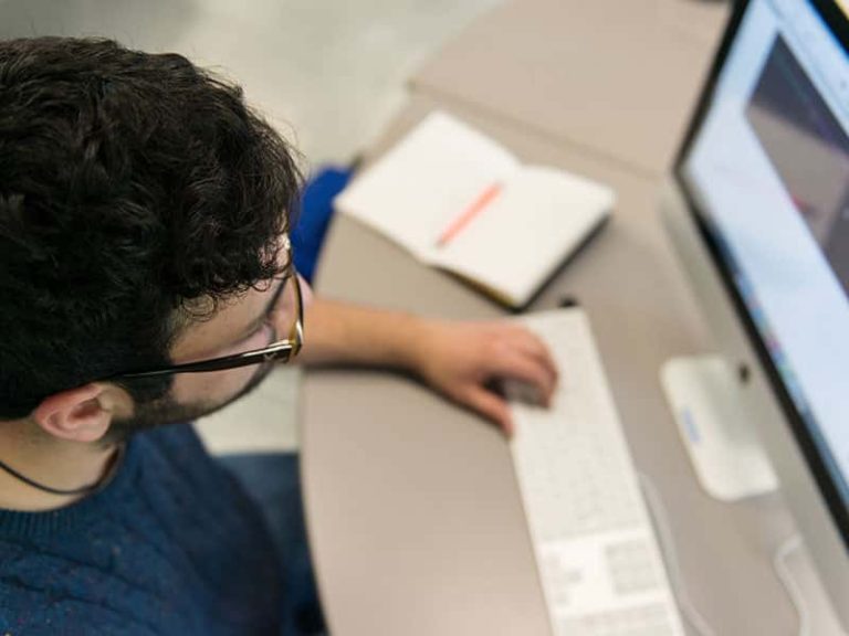 Image of a student sat at a mac computer