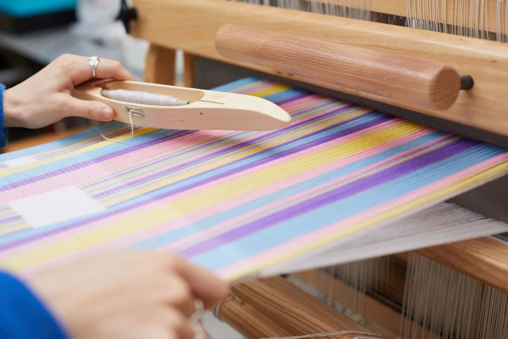 Rebecca Hiscock, BA Textile Design student at Norwich University of the Arts on a loom in the textiles workshop