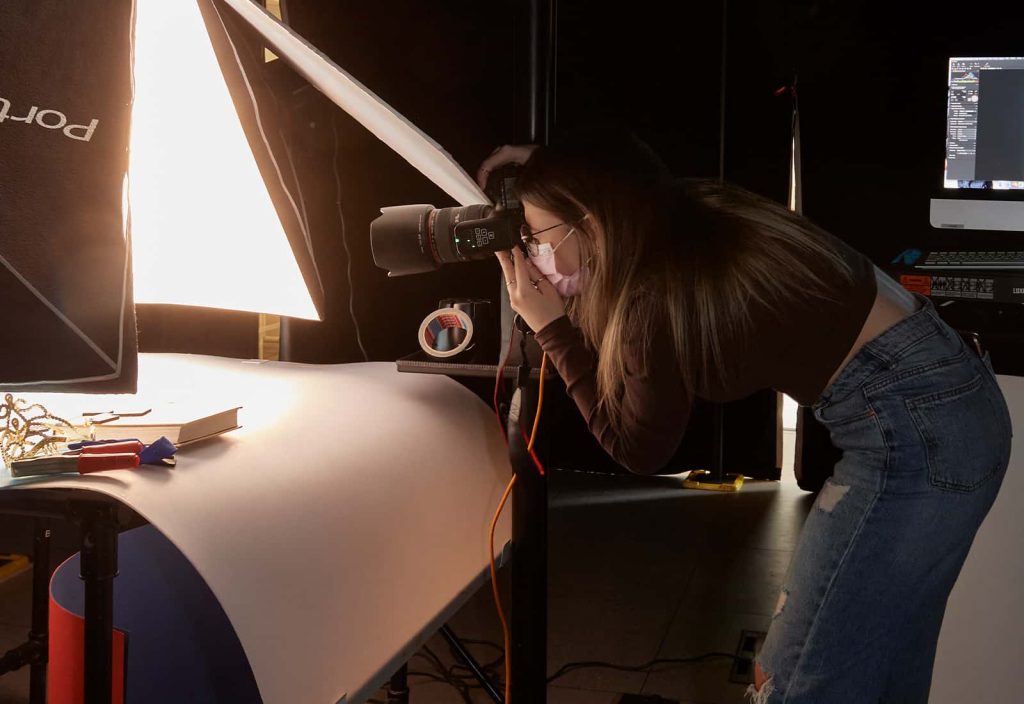 A student leans in with a DSLR to shoot their project in the animation studio