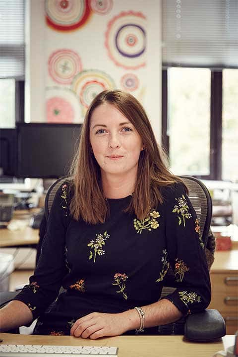 Image of a female sitting in a chair in a graphics studio looking to camera