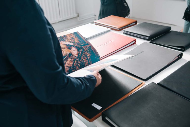 Photograph from BA Degree Show 2017 of someone looking through Fashion portfolios laid out on a table