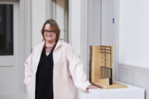 Angela Beckett stood in a black dress and white coat looking at the camera