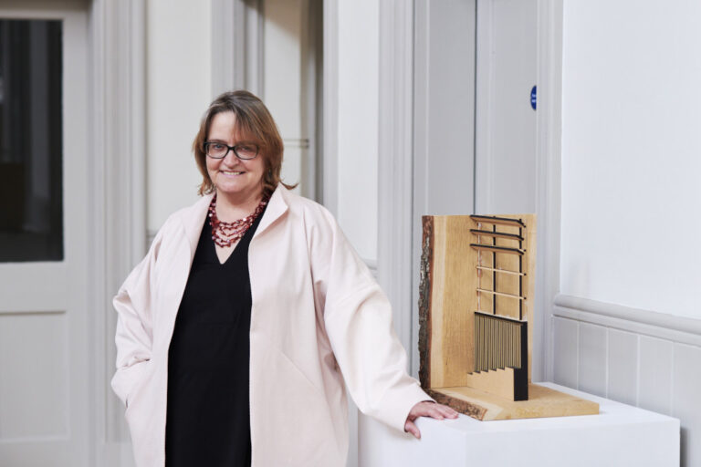 Angela Beckett stood in a black dress and white coat looking at the camera