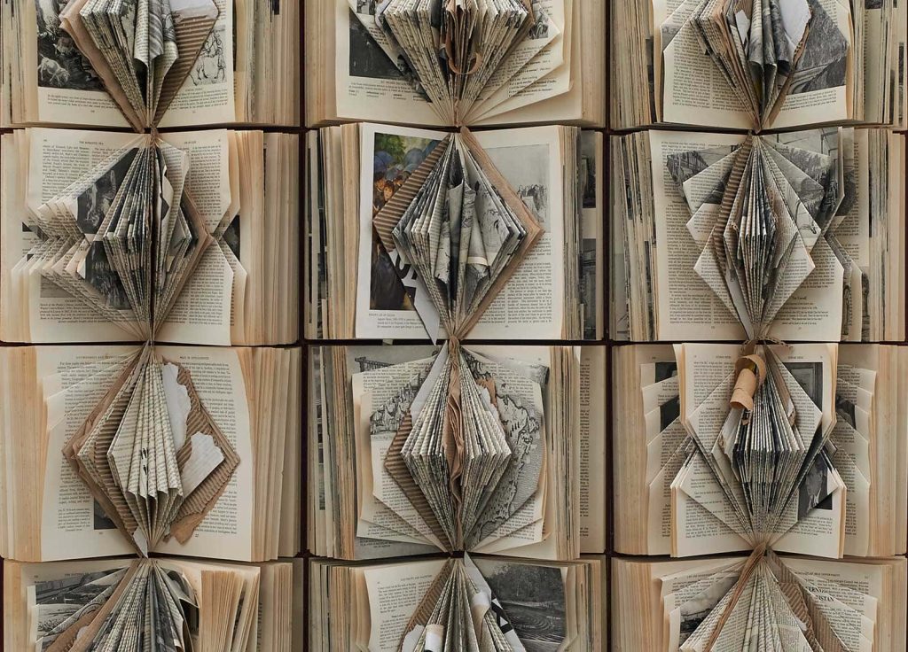 Image of books which have been cut and folded to create concertina shapes on the inside of the books