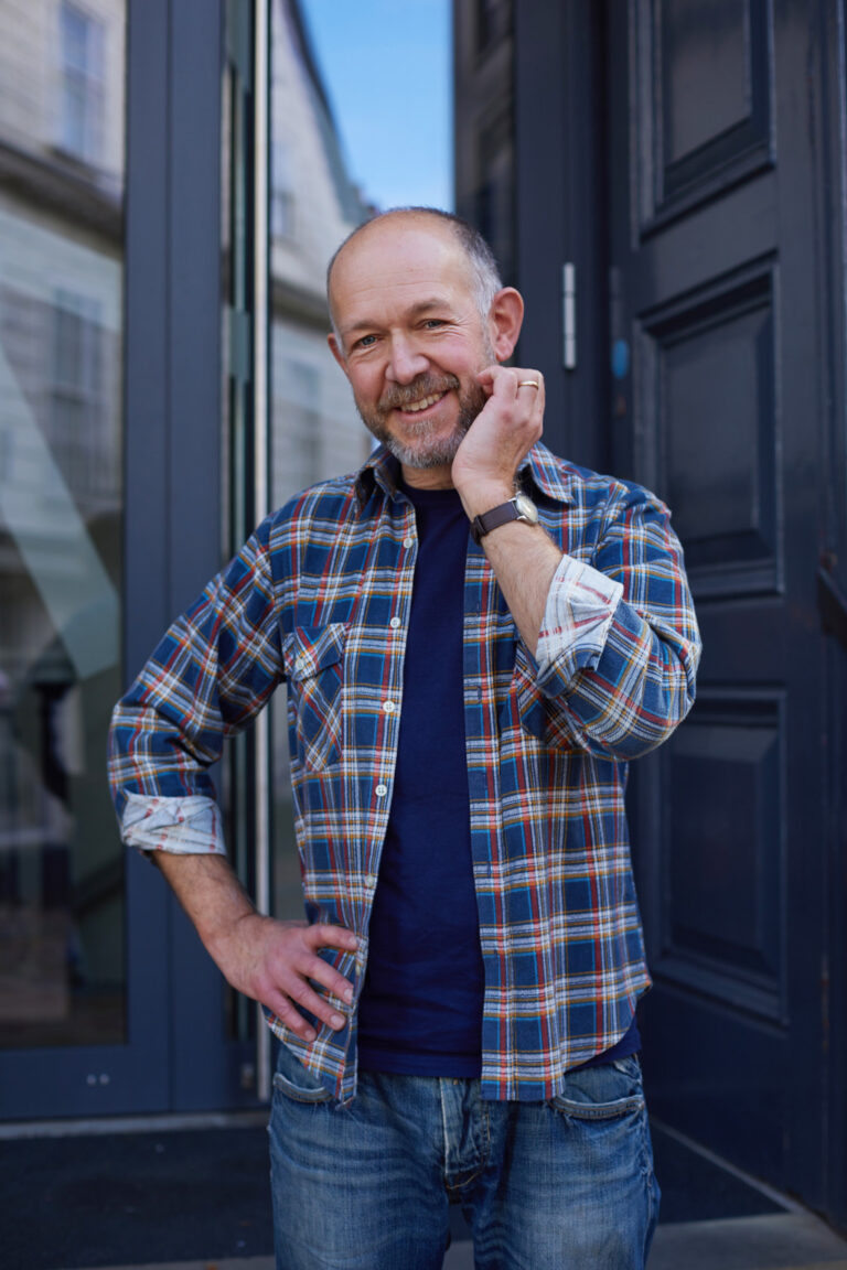 Richard Bracewell, Lecturer on BA Film and Moving Image Production standing on the steps of Boardman House at Norwich University of the Arts