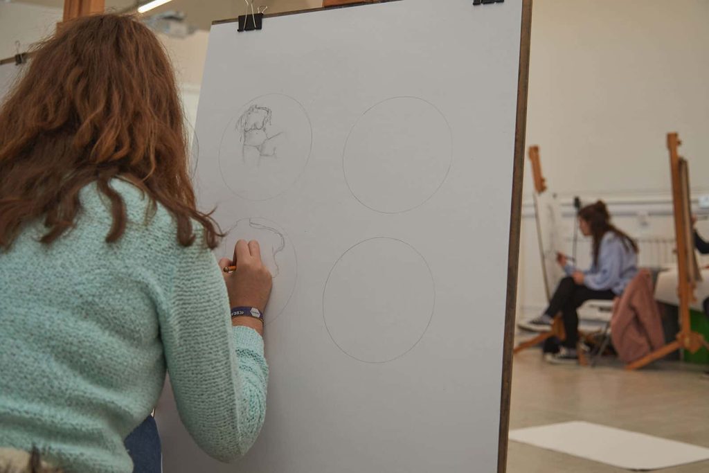 Student at Norwich University of the Arts drawing on an easel in Drawing Studio