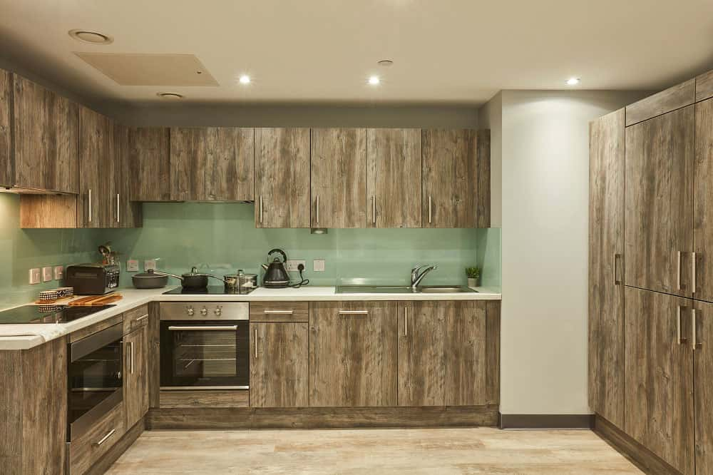 Crown Place kitchen area with wooden cabinets and floor, and glass splashback