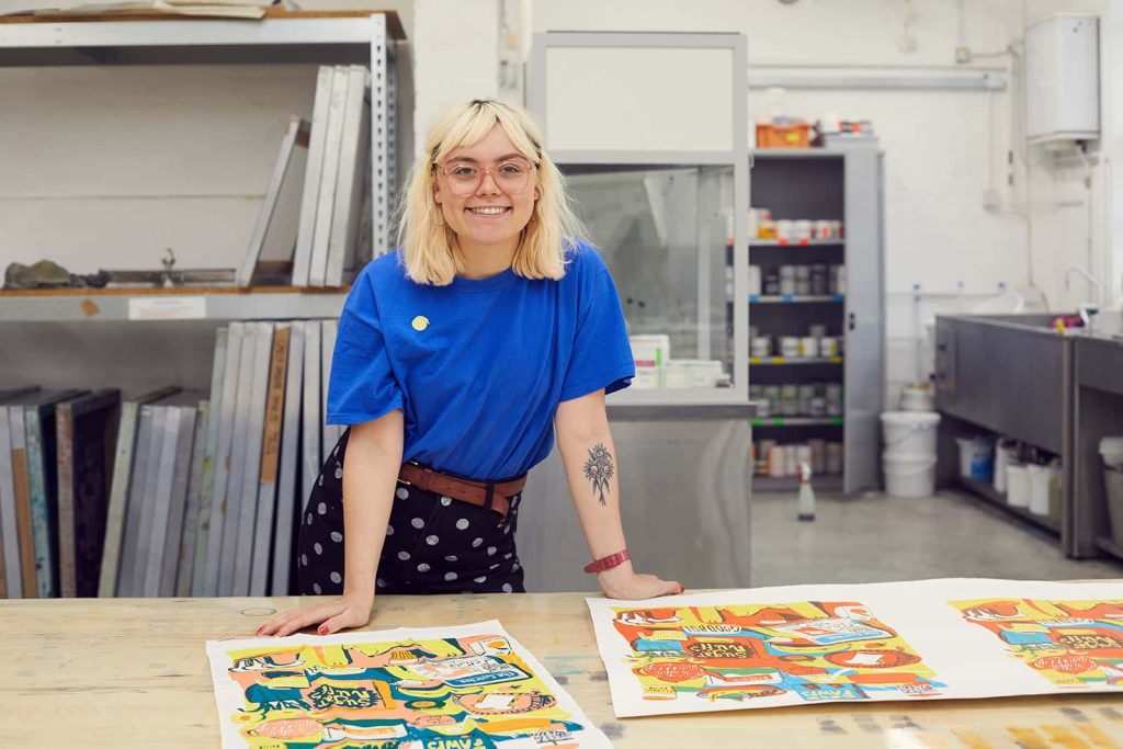 Florence Poppy Dennis stands by her BA Textile Design student work at Norwich University of the Arts in the textiles workshop