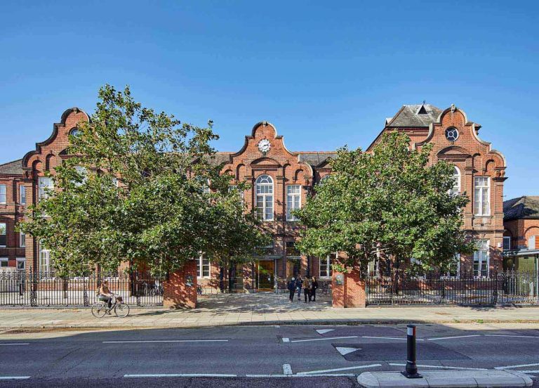 External photo of Norwich's Duke Street building with blue skies and two green trees in front