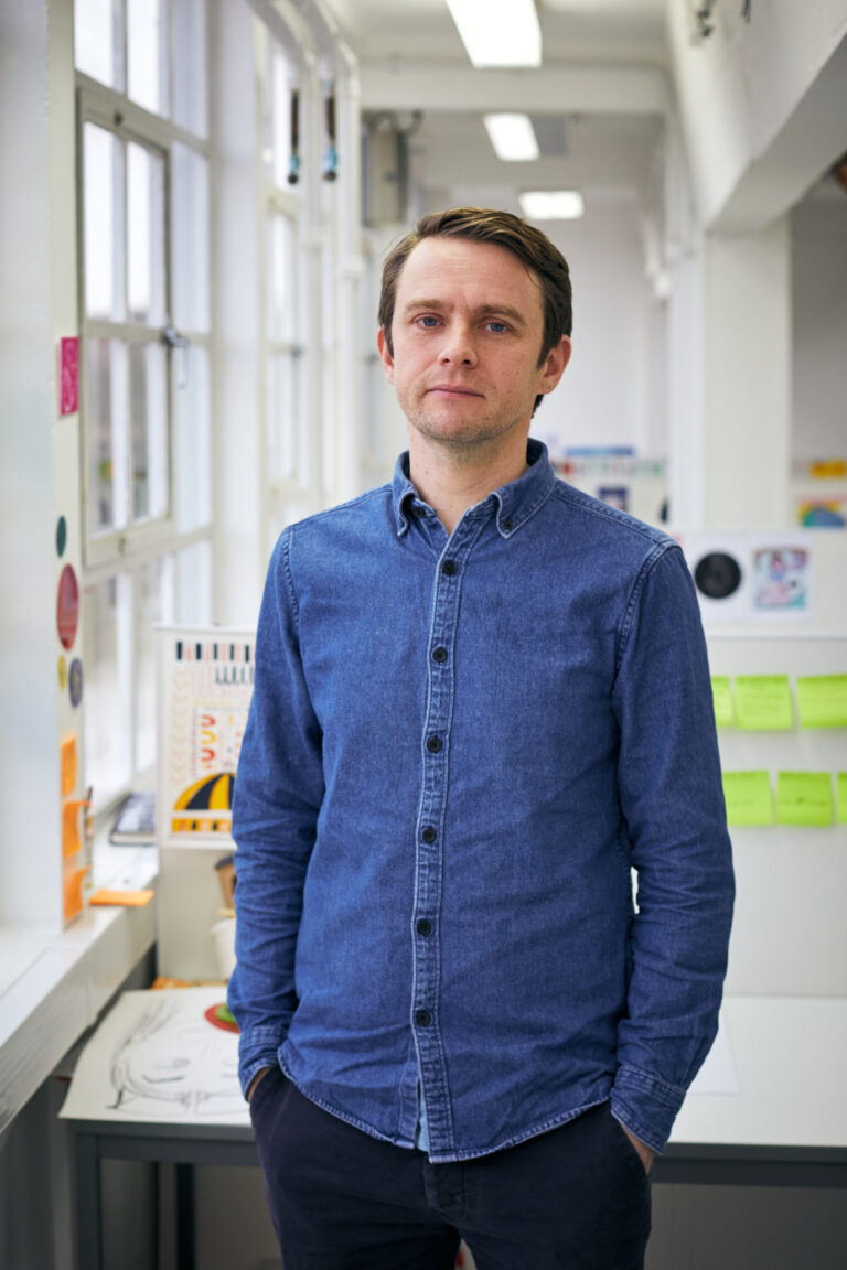 BA Illustration Lecturer Rob Nicol standing in an illustration studio at Norwich University of the Arts wearing a denim shirt