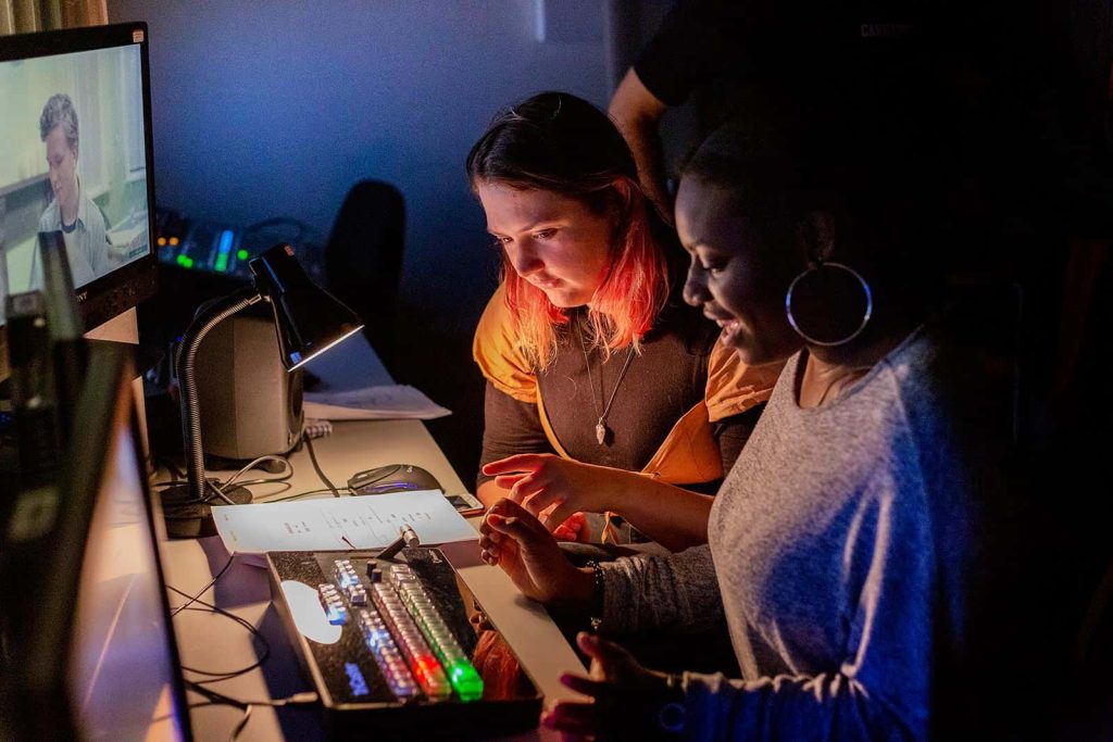 Two students at Norwich University of the Arts sit in the control room of the Sir John Hurt Film Studio