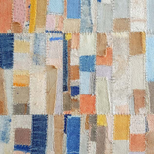 Square artwork in blues, yellows, oranges and creams made up of different sized square and rectangular pieces of fabric
