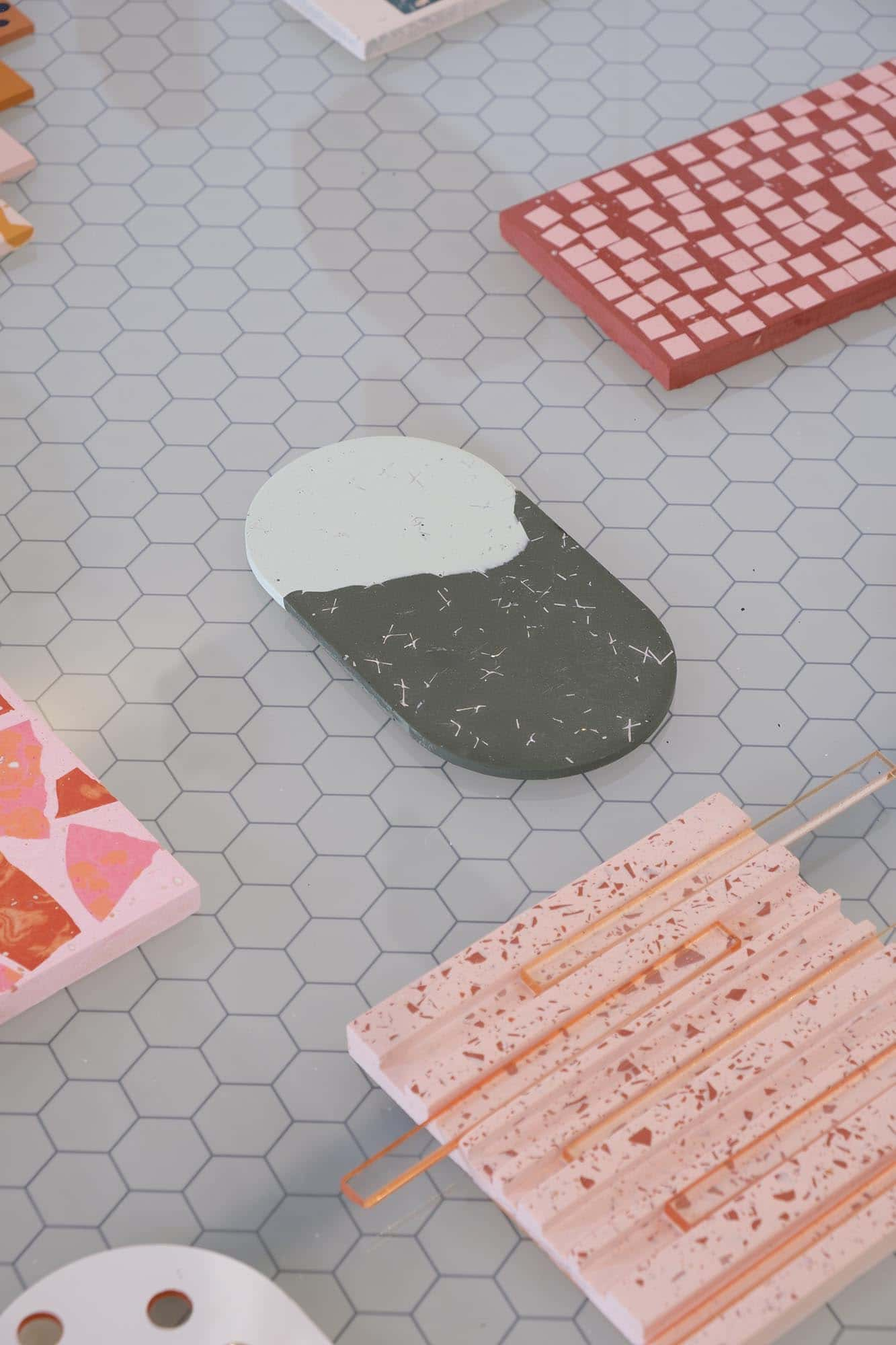 A grey table with individual terrazzo pieces in pink, red, coral and grey in different shapes placed apart from each other