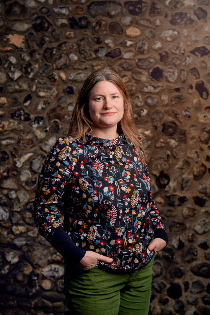 BA Animation and Visual Effects Lecturer Anna Blagrove standing in front of a stone flint wall