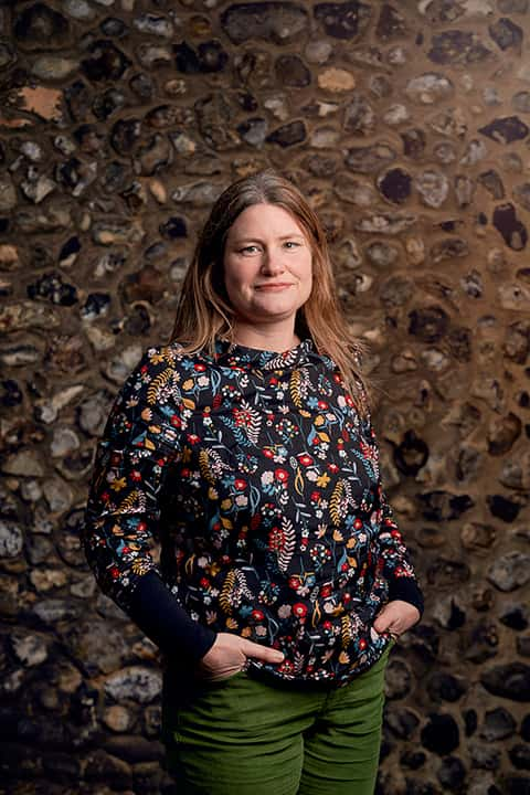 BA Animation and Visual Effects Lecturer Anna Blagrove standing in front of a stone flint wall