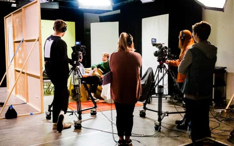 Norwich University of the Arts students working with camera equipment on a makeshift set in the Sir John Hurt studio on campus