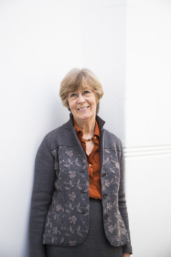 Professor Marcia Pointon standing against a wall at Norwich University of the Arts wearing a jacket