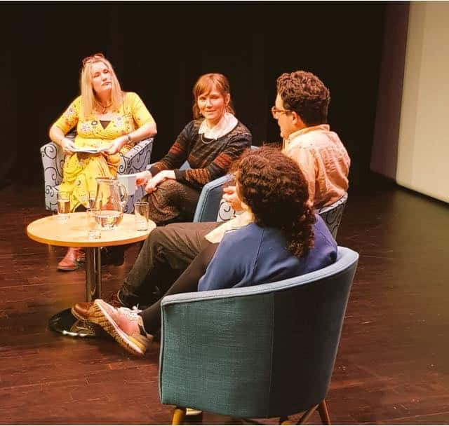 four people sitting on chairs around a table having a discussion