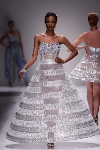 Person walking down catwalk in silver mesh dress