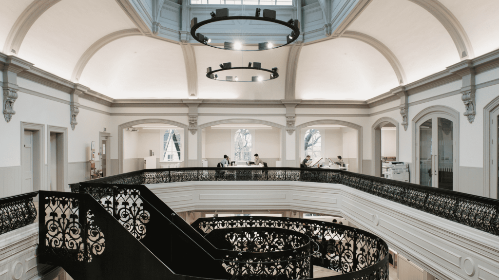 The interior of Boardman House, Norwich showing a staircase and large hanging lights and skylights