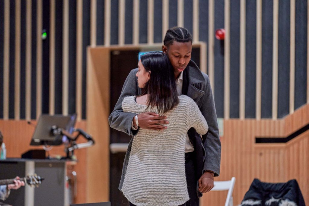 Two BA Acting students embrace solemnly on stage