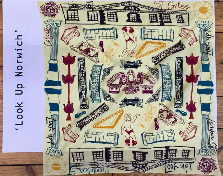 Top down view of a pale yellow square scarf laid flat. Across the scarf are hand drawn illustrations of historical buildings, statues, architectural features and crests that can be found around Norwich. Designed by BA Textile Design student Emma Strudwick