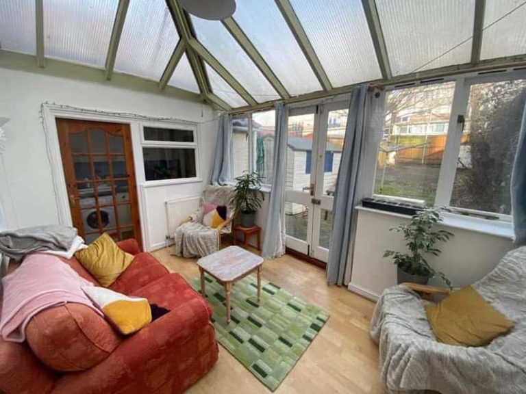 A photo of a shared conservatory in private student accommodation. Two sofas are placed around a coffee table, overlooking the garden.