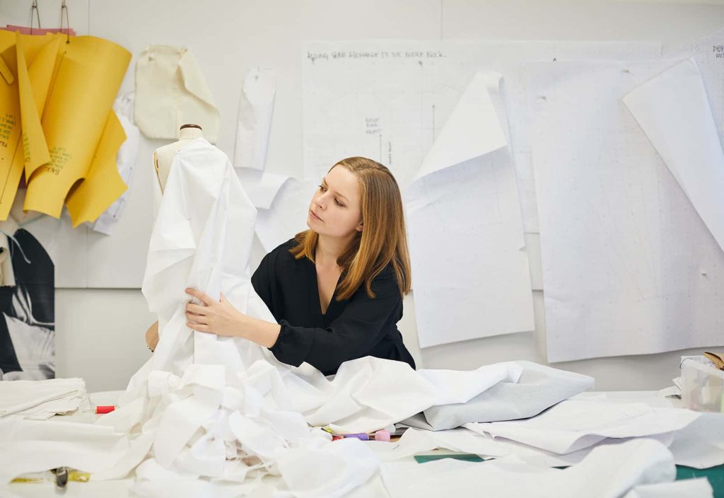 MA student Emily Cannell works with white fabric on a mannequin