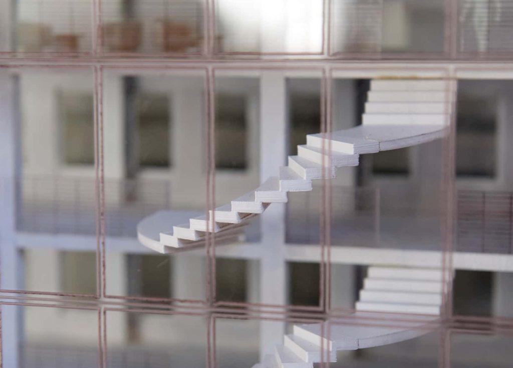 A small but detailed prototype of a floating spiral staircase inside a building with glass fascia, the staircase has been neatly cut from softwood or foam and glued to create an accurate 3D model of the students project.