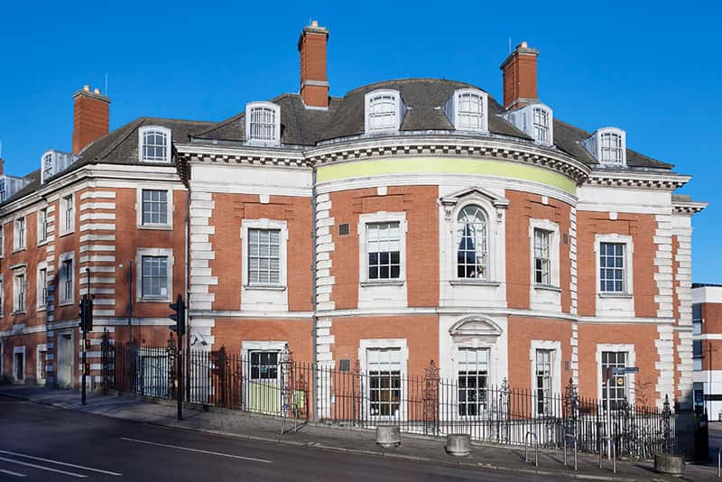 A photograph of Grade II listed building 20 Bank Plain, Norwich, against a bright blue sky