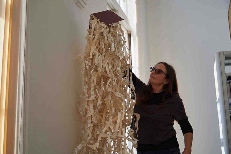 Person hanging book with hanging dismantled pages from library window