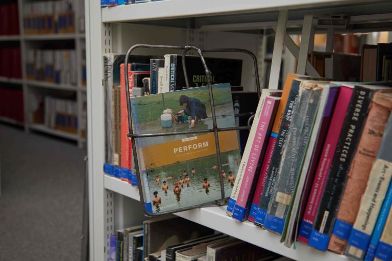 Book about performance on library shelf with metal cage frame encapsulating it