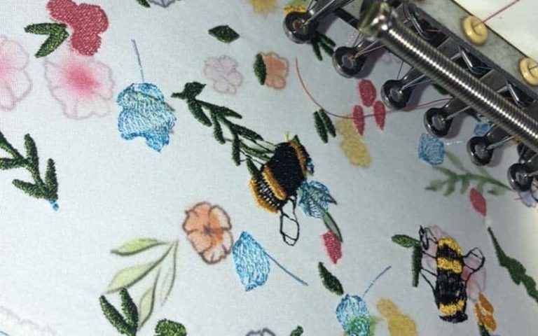 Colourful embroidary of bees and flowers on a white fabric