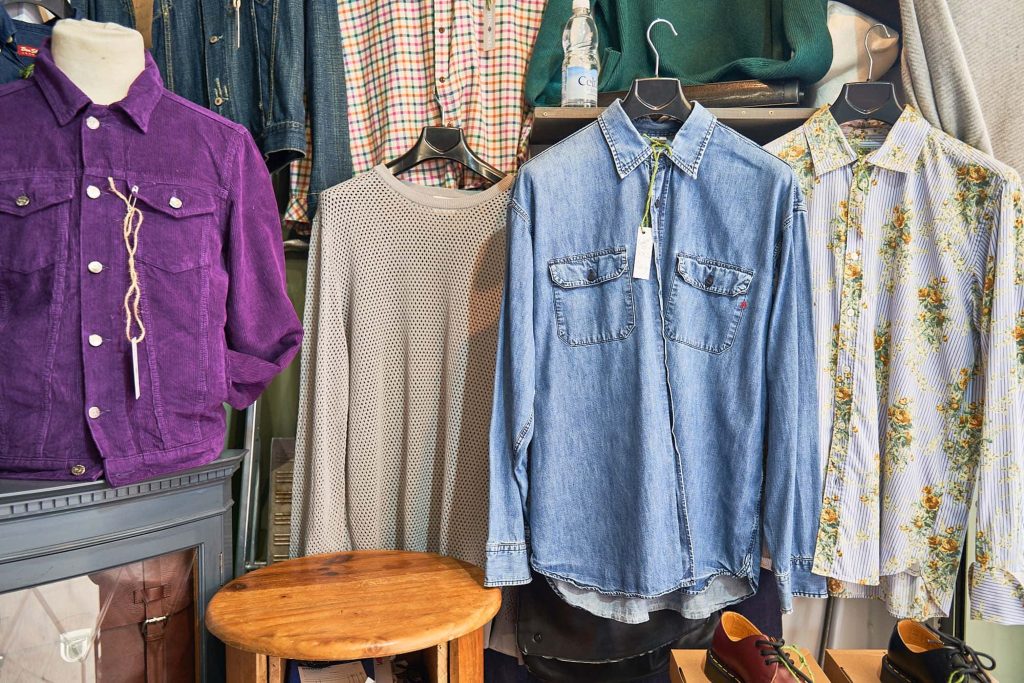 Three shirts hanging on a charity shop wrack, all different colours in Norwich