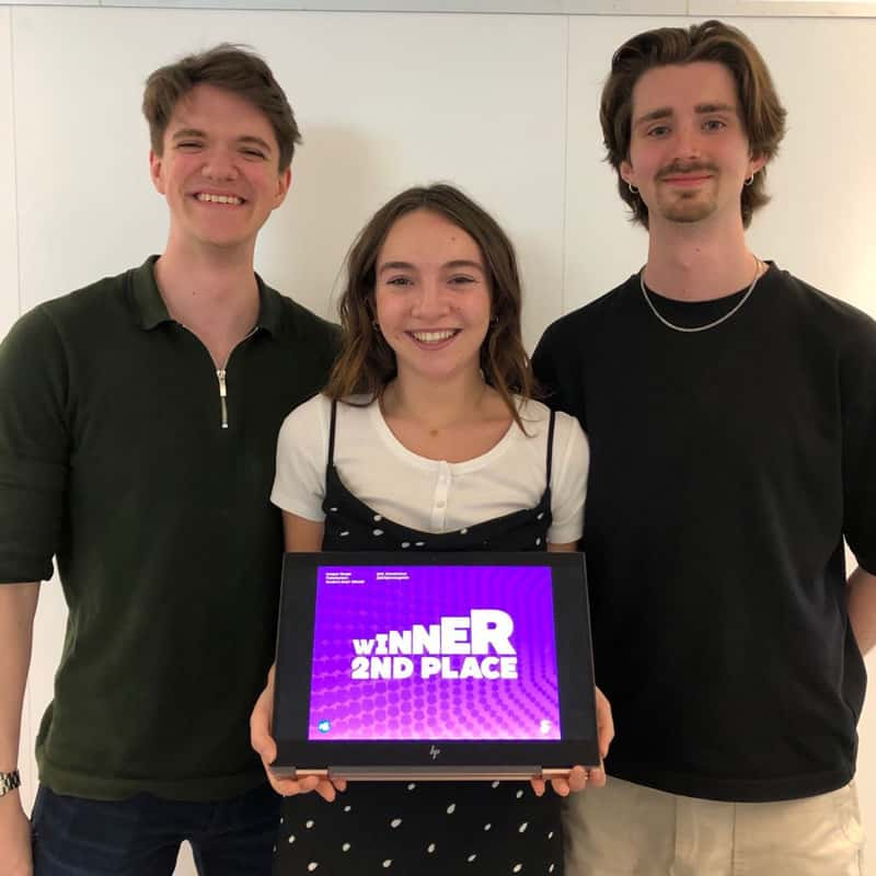 Graphics students Reiss Tozer, Iona Mound and Ben Mountford standing side by side, with Iona holding an iPad displaying a graphic saying 'Winner 2nd Place'