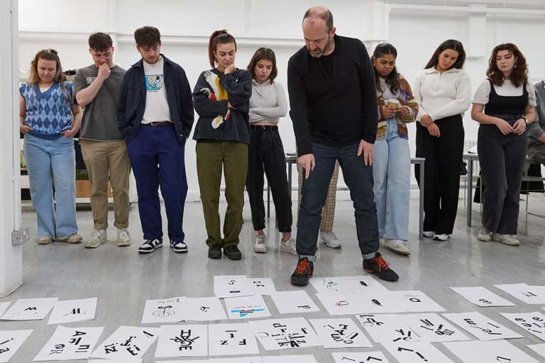 Image showing person leading workshop talking through student work on floor with students in background