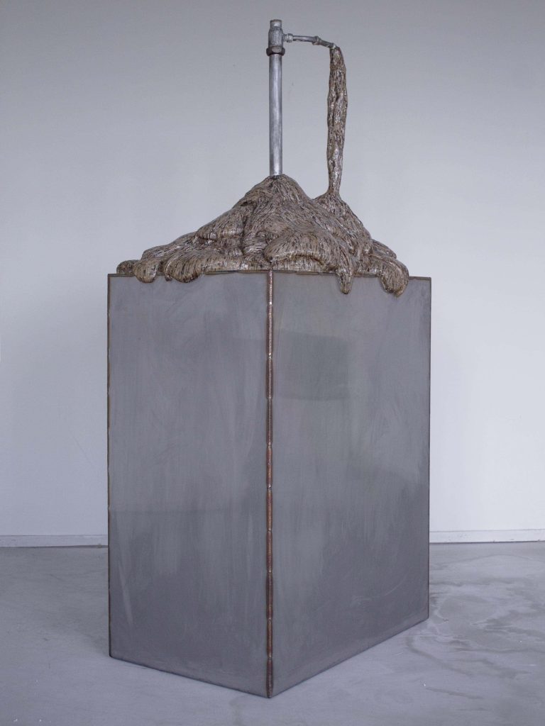 Image of metal scultpure with metal tap emerging from the top spouting shredded images