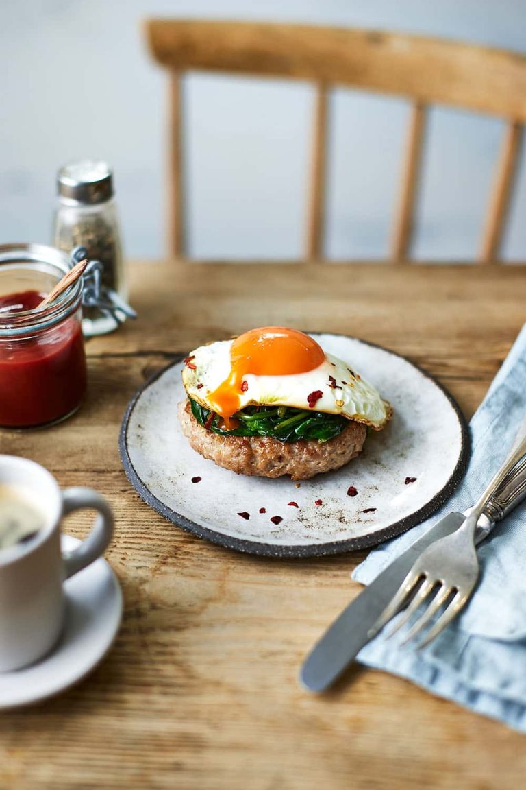 Photograph of dinner table with plate containing bagel with avocado and pouched egg on top