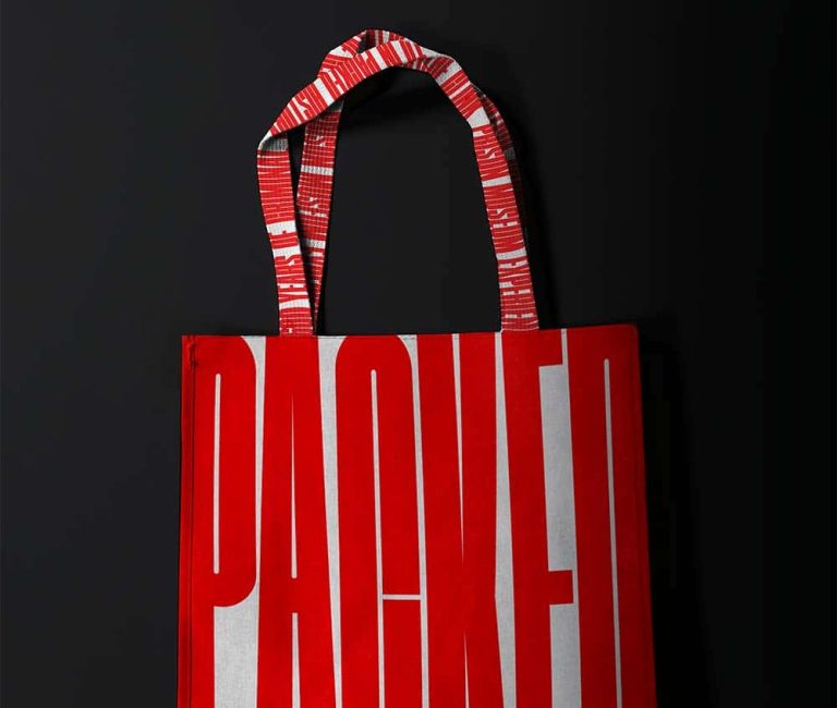 Mock up of tote bag reading "Packed" in bold red lettering