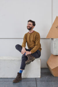 Senior Fine Art Lecturer Ben Mc Donnell sitting on a concrete block in a studio