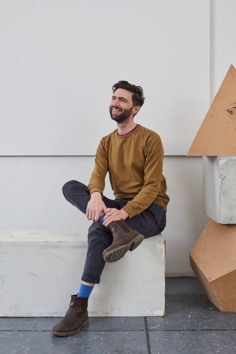 Senior Fine Art Lecturer Ben Mc Donnell sitting on a concrete block in a studio